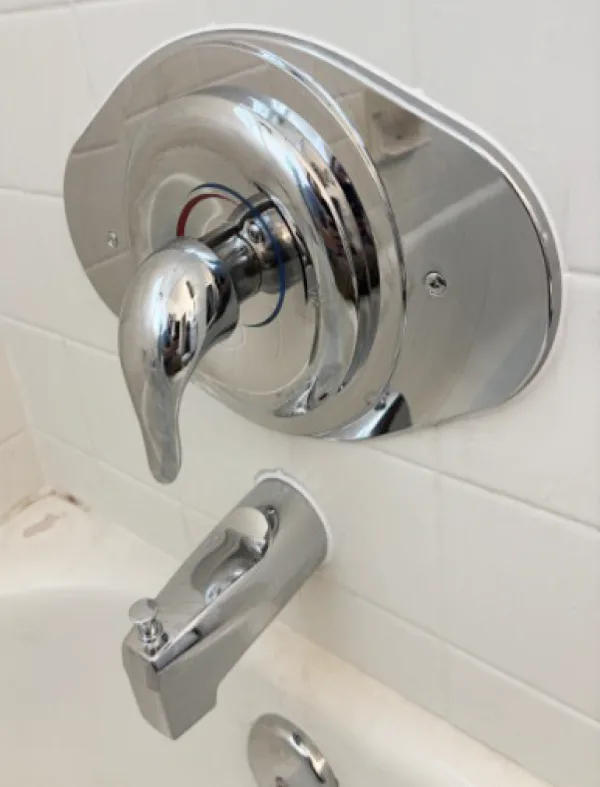 Chrome shower valve trim and handle installed on a tiled bathroom wall