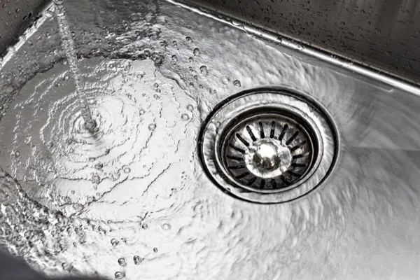 Water swirling down the strainer of a stainless steel sink