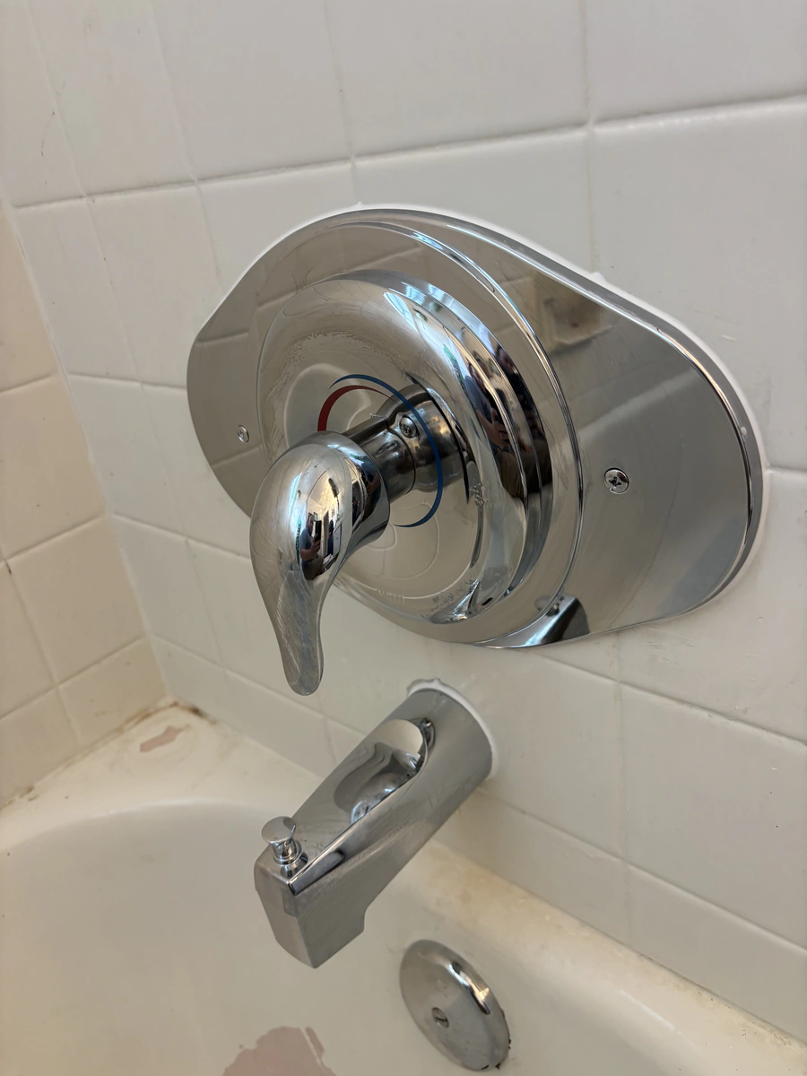 Chrome shower valve trim and handle installed on a tiled bathroom wall