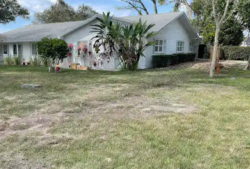 Front lawn of a single story Maitland home with a wide strip of bare backfilled sand running out toward the street