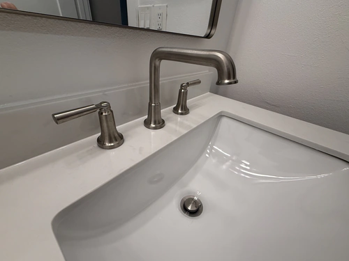 Brushed nickel widespread faucet on a white quartz vanity top with an undermount sink
