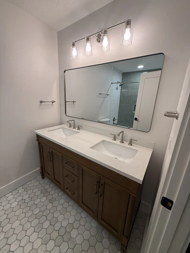 Winter Park bathroom with a dark wood double vanity, two undermount sinks, brushed nickel widespread faucets, a wide framed mirror and hexagon floor tile