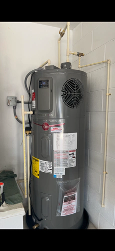 Grey Rheem ProTerra hybrid heat pump water heater in a garage with its display reading 120 degrees and new CPVC piping above it