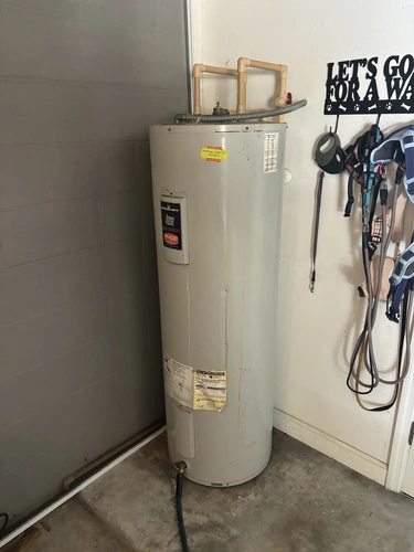 Aging white electric water heater tank standing in the corner of a Lake Mary garage