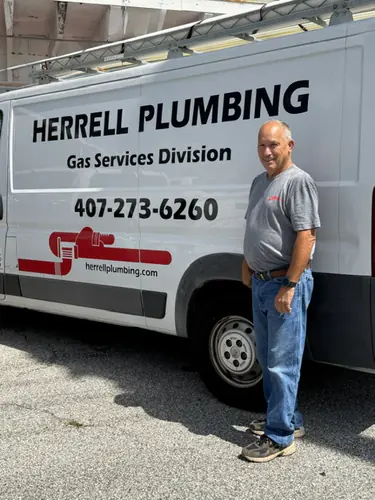 Herrell Plumbing technician standing in front of a lettered service truck at a Windermere home